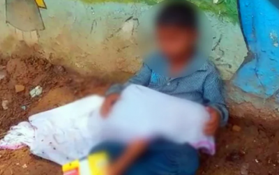 8-year-old innocent sits outside hospital with younger brother's 'body' in his lap