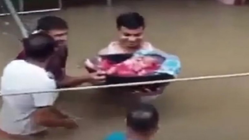 बाढ़ के बीच टोकरी में बच्चे को लेकर निकला पिता, वायरल हो रहा वीडियो